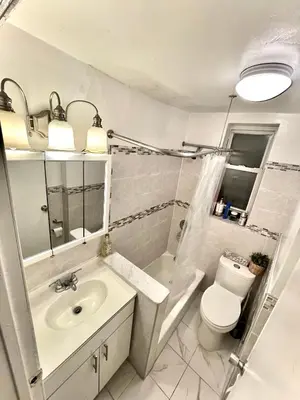 a white bathroom with a sink and a toilet at Bedroom 10 mins to Times Square! and is first floor in Queens