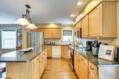 a kitchen with wooden cabinets and granite counter tops at 5 Mi to Mt Snow West Dover Getaway with Hot Tub in Brattleboro