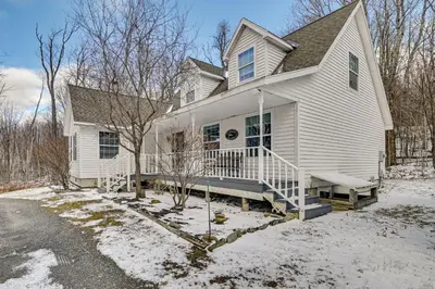 a white house with a porch in the snow at 5 Mi to Mt Snow West Dover Getaway with Hot Tub in Brattleboro