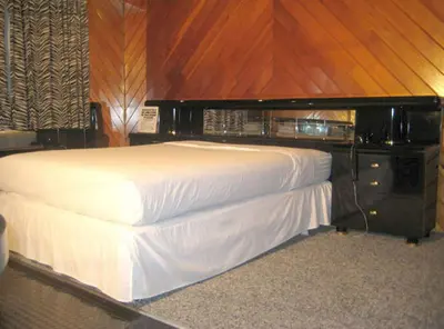 a bedroom with a white bed with a wooden wall at Commack Inn in Commack