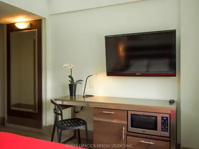 a room with a desk with a microwave and a tv on the wall at Commack Inn in Commack