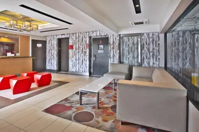 a lobby with a couch and a table and red chairs at Commack Inn in Commack