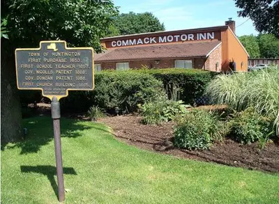 a sign in the grass in front of a museum at Commack Inn in Commack
