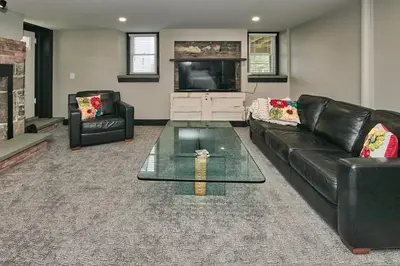 a living room with a black leather couch and a tv at Craftsman Hideaway at the 1841 Farmhouse in Chester