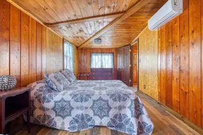 a bedroom with a bed in a wooden cabin at Catskills Cottage with Deck, 7 Mi to Hunter Mtn in Elka Park