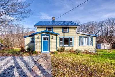a small yellow house with a blue door at Catskills Cottage with Deck, 7 Mi to Hunter Mtn in Elka Park