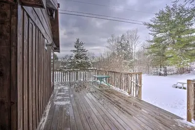 a wooden deck with a bench on it in the snow at Cozy Catskills Home with Pond on 2 Acres! in Earlton