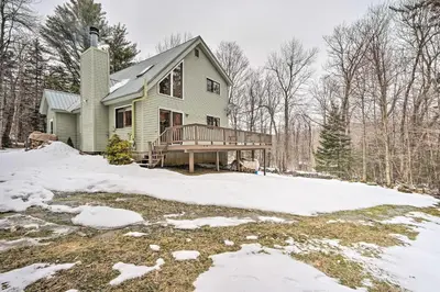 a green house with a deck in the snow at Relaxing Home Mins from Mt Snow, Hiking, and Lakes in Dover