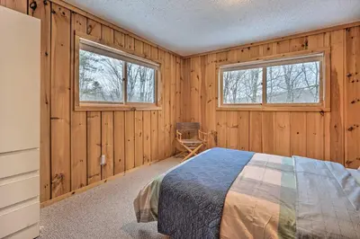 a bedroom with wooden walls and a bed and two windows at Relaxing Home Mins from Mt Snow, Hiking, and Lakes in Dover