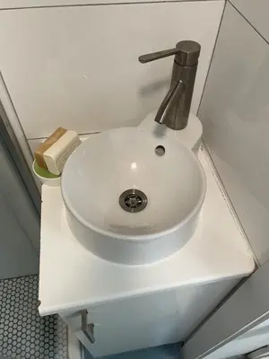 a white sink in a bathroom with a fosset at California guest house in Greenwich