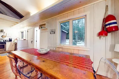 a dining room with a wooden table and a kitchen at Little Red in Wilmington