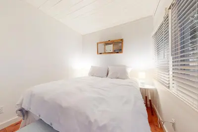 a white bedroom with a white bed and a window at Little Red in Wilmington