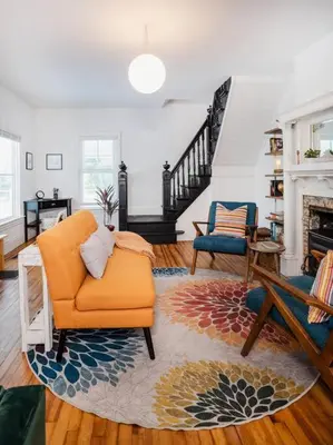 a living room with an orange chair and a fireplace at 1850 Catskills Farmhouse on 8 acres in E. Durham in East Durham