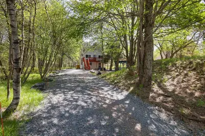 a dirt road with a house in the middle of a forest at Camp Cedar:7 miles to Camelback, 5 to Kalahari! in Long Pond