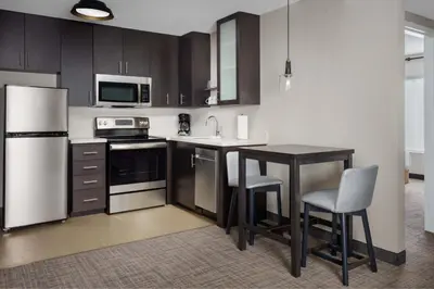 a kitchen with black cabinets and a table and chairs at Residence Inn by Marriott New Haven Hamden in Hamden