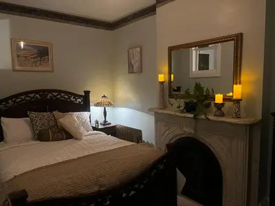a bedroom with a bed with a fireplace and a mirror at 1 Br Private Victorian Apt in convenient City location on half acre sleeps 4 in Poughkeepsie