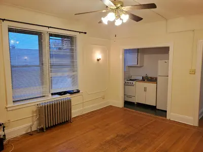 an empty living room with a ceiling fan and a kitchen at Comfy stay – sleeps 4 (Hoboken) in Hoboken