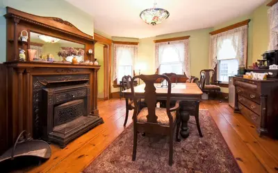 a dining room with a table and a fireplace at Blooming Inn Shelburne Falls in Shelburne Falls
