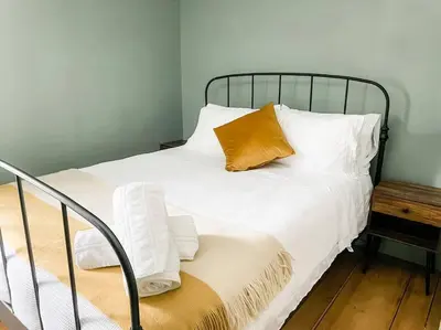 a bed with white sheets and an orange pillow on it at The Brookside Lodge & Cottage in Dover