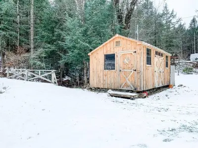 a wooden shed in a snow covered yard at The Brookside Lodge & Cottage in Dover