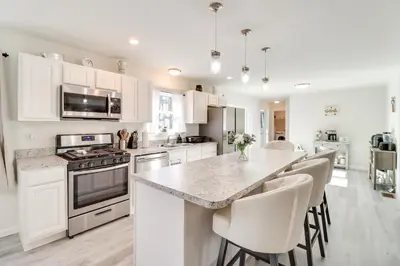 a kitchen with white cabinets and a kitchen island with chairs at 3 Mi to Kalahari Pocono Summit Home with Pool Table in Pocono Summit