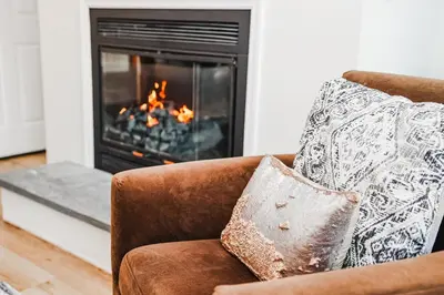 a couch with a pillow in front of a fireplace at NEWLY REMODELED FOUR BEDROOM All SEASON CONDO W MOUNTAIN VIEWS in East Jewett