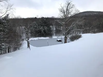 a field covered in snow with a car in it at Mountain Condo with Modern Cabin Style in East Jewett