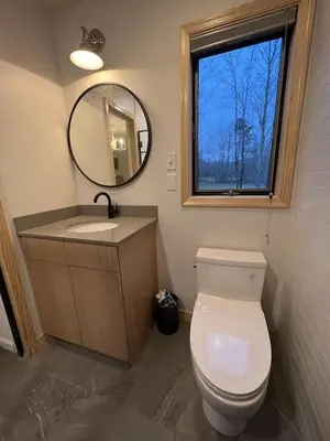 a bathroom with a toilet and a sink and a mirror at Mountain Condo with Modern Cabin Style in East Jewett