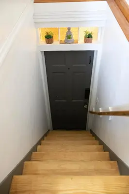 a stairway with a black door and potted plants at Cozy Tiny Haus Apt in Torrington
