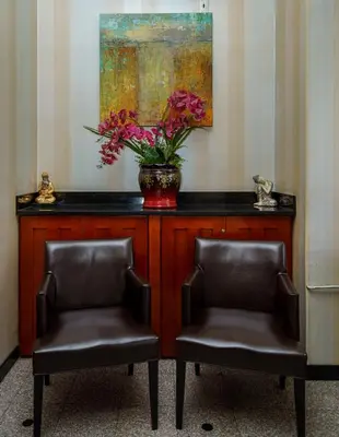 two chairs and a vase with flowers on a counter at Sky Hotel Flushing/Laguardia Airport in Queens