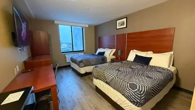 a hotel room with two beds and a desk at Sky Hotel Flushing/Laguardia Airport in Queens