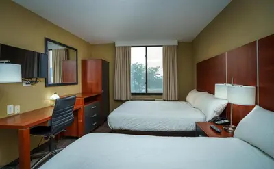 a hotel room with two beds and a desk at Sky Hotel Flushing/Laguardia Airport in Queens
