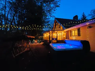 a house with a lit up backyard at night at Spacious Gateway, Walk to POOL & BEACH, Hot tub, Game room in Pocono Country Place