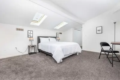 a white bedroom with a bed and a desk at Exquisite Downtown Loft Apartment in Hartford