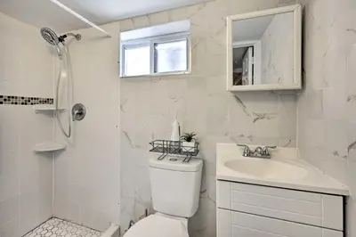 a white bathroom with a toilet and a sink at Charming New York Escape Near Central Park! in Jericho
