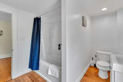 a bathroom with a toilet and a blue shower curtain at The Hill All Star Baseball Rentals in Oneonta