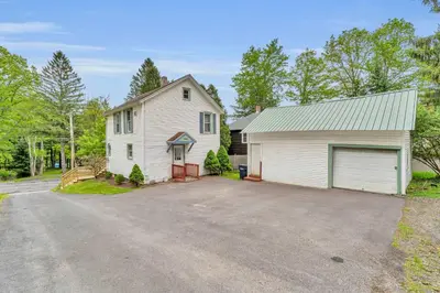 a white house with a garage and a driveway at The Hill All Star Baseball Rentals in Oneonta