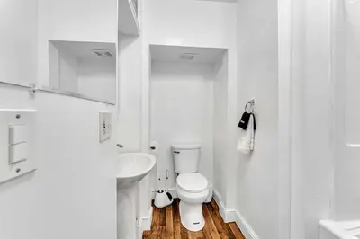 a white bathroom with a toilet and a sink at The Hill All Star Baseball Rentals in Oneonta