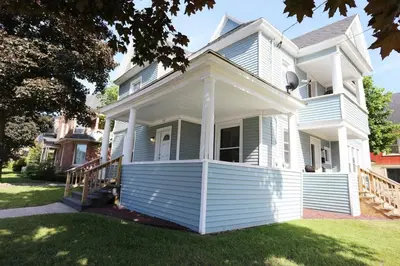 a white house with a porch on a lawn at 2nd Base Apt 2 All Star Baseball Rentals in Oneonta