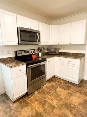 a kitchen with white cabinets and a stove and microwave at Center Field All Star Baseball Rentals in Oneonta