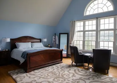 a bedroom with blue walls and a bed and two windows at Grand Slam Lake House Cooperstown Dreams Park in Cooperstown