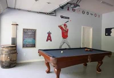 a man is holding a bat over a pool table at Grand Slam Lake House Cooperstown Dreams Park in Cooperstown