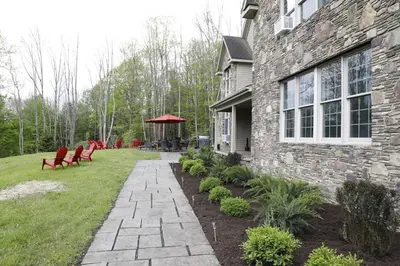 a stone house with a patio and a gazebo at Grand Slam Lake House Cooperstown Dreams Park in Cooperstown