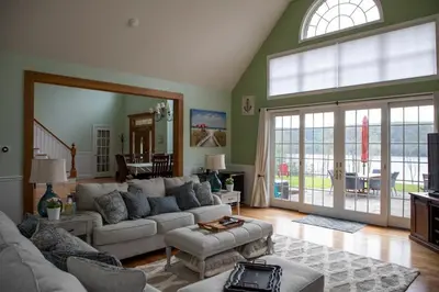 a living room with a couch and a large window at Grand Slam Lake House Cooperstown Dreams Park in Cooperstown