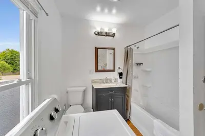 a white bathroom with a toilet and a sink at Left Field All Star Baseball Rentals in Oneonta