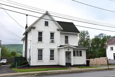 a white house on the corner of a street at Left Field All Star Baseball Rentals in Oneonta