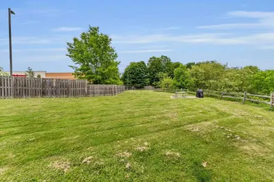 a large grass field with a fence and trees at Left Field All Star Baseball Rentals in Oneonta