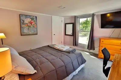 a bedroom with a bed and a dresser and a television at The Bullpen All Star Baseball Rentals in Oneonta
