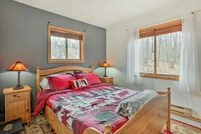 a bedroom with a bed and two windows at 4 Mi to Tubing Cozy Bushkill Cabin with Deck! in Bushkill