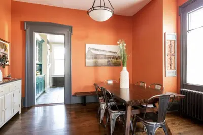 a dining room with orange walls and a wooden table and chairs at Hudson Valley Retreat in Downtown Hudson, NY - Sleeps 16-20 in Hudson